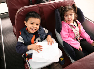 Two children in car seats on a bus.
