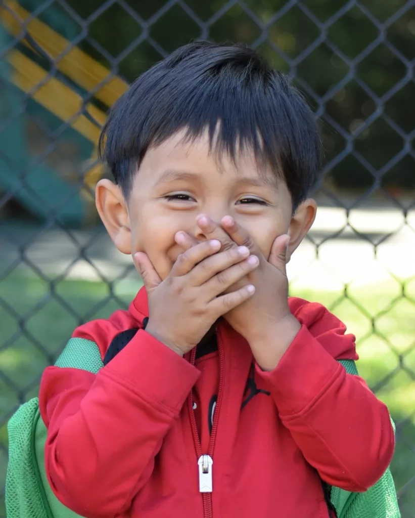 smiling boys with hands on mouth